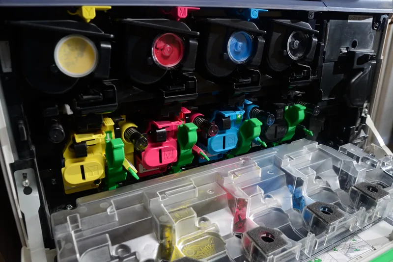 Open CMYK toner cartridge bay in a color copier, showing yellow, magenta, cyan and black toner and drum units